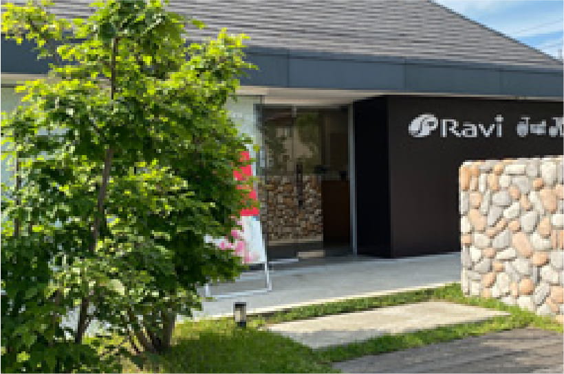 緑の木々と自然石の壁に囲まれた「Ravi Just Nail」のサロン入口