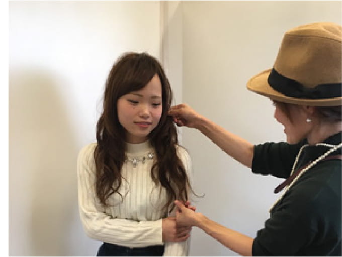 美容師が女性の髪型を丁寧に確認しながらスタイリングを提案している場面
