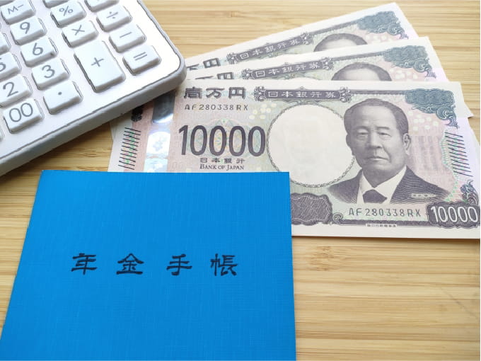 木目調のテーブルに置かれた青い「年金手帳」