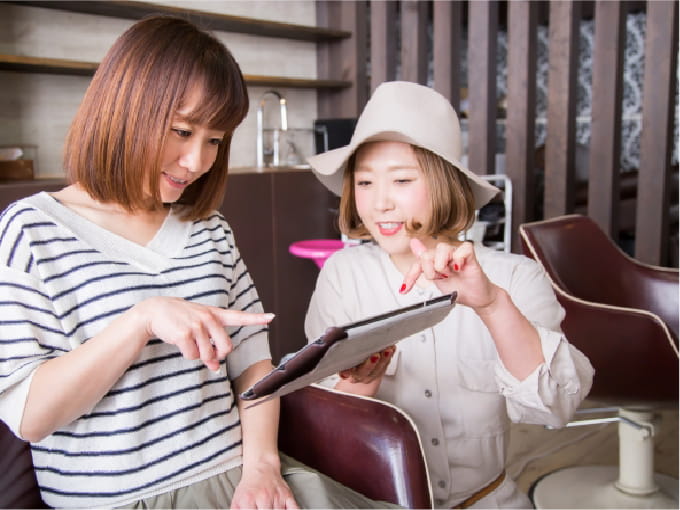 美容師がタブレットを使って、お客様とヘアスタイルの相談をしている場面