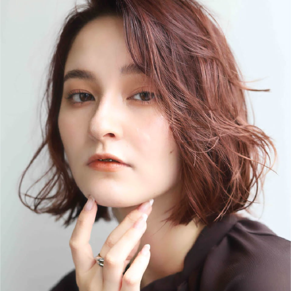 赤みがかったショートボブヘアの女性で、髪は自然な動きのあるスタイル