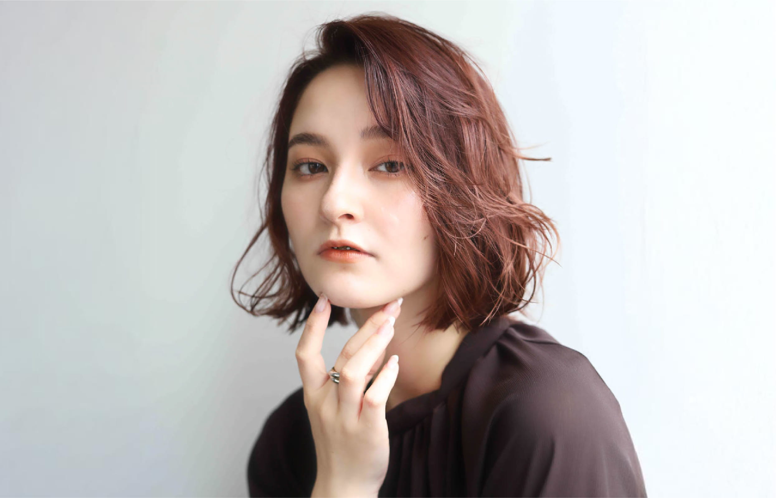 赤みがかったショートボブヘアの女性で、髪は自然な動きのあるスタイル